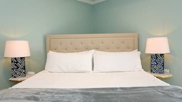 A bed with a tufted headboard, two bedside lamps with leaf patterns, and a white bedspread.