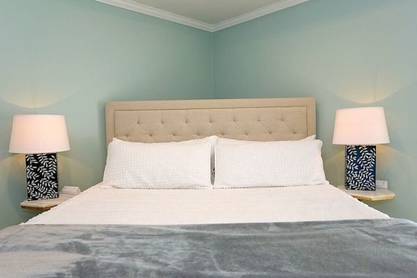 A bed with a tufted headboard, two bedside lamps with leaf patterns, and a white bedspread.
