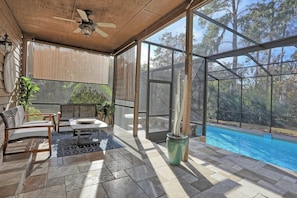 A covered outdoor area with a pool, seating, and a view of trees. - Wilmington Island Pool Oasis: Screened Pool, Sleeps 14, Near Tybee & Downtown (Savannah)