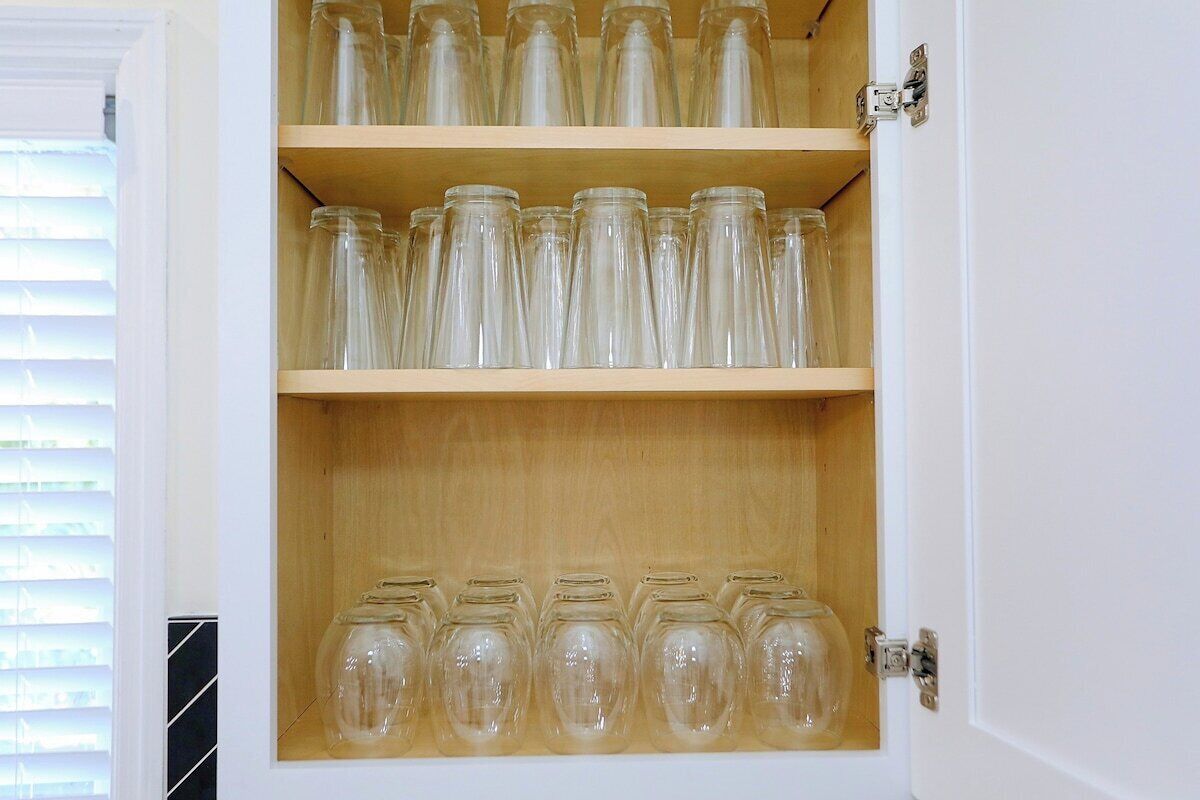 Et skab med flere hylder fyldt med transparente glasbeholdere.