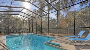 A clear pool with a metal roof and lounge chairs.