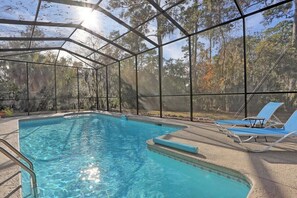 Une piscine aux eaux cristallines, surmontée d’un toit en métal et bordée de chaises longues.
