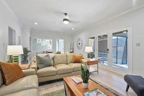 A modern living room with a sofa, coffee table, and a dining area. - Wilmington Island Pool Oasis: Screened Pool, Sleeps 14, Near Tybee & Downtown (Savannah)