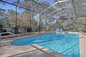 An indoor swimming pool with a glass enclosure, surrounded by trees.