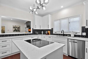 Een moderne keuken met witte kasten, een centraal eiland, een roestvrijstalen vaatwasser en een zwart-wit houten vlechtachtergrond.