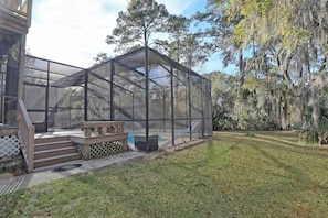 A covered outdoor area with a wooden deck, a bench, and a small table.