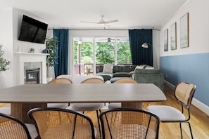 A modern living room with a dining area, large windows, and a fireplace.