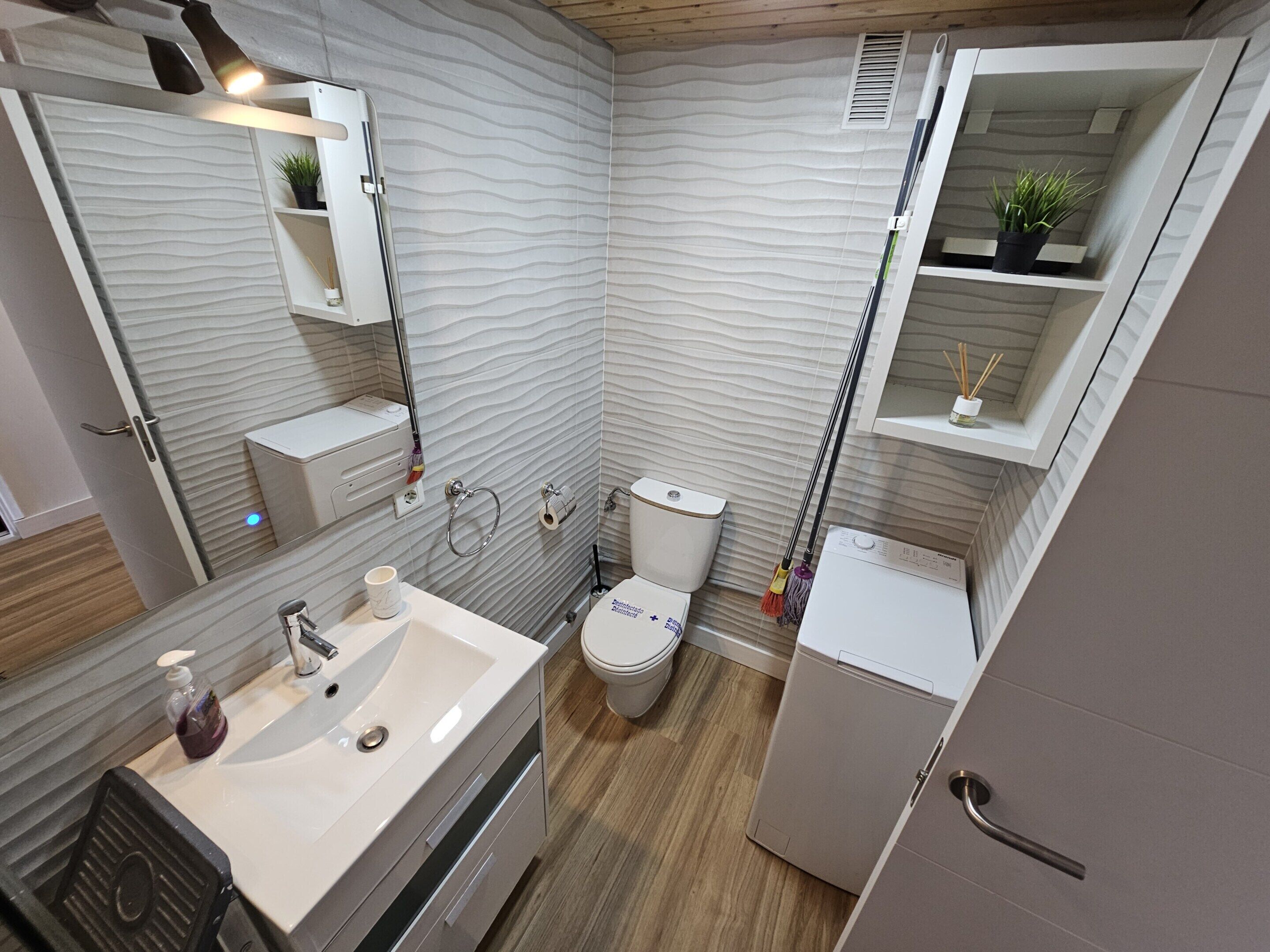 A modern bathroom with a toilet, sink, and mirror.