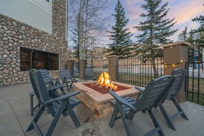 An outdoor seating area with a stone fire pit and chairs. - Grand Lodge CB — Ski-In/Out | Hot Tub + Pool | Sleeps 4 + Pets OK (Crested Butte)