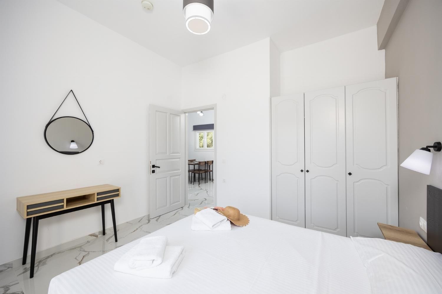 Un dormitorio moderno con una cama grande, una mesita de noche, un espejo y un armario.