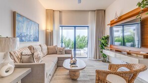 A modern living room with a sofa, coffee table, and wicker chairs. - ENJOY THIS BEAUTIFUL APARTMENT IN PUNTA CANA (Higüey)