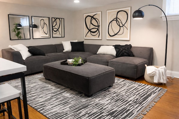 A modern living room with a sectional sofa, a coffee table, and abstract art on the walls.