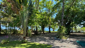 A garden with a gravel path, trees, and a view of the sea.