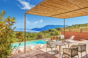 A poolside area with a view of the sea and hills, covered patio, and outdoor seating. - Villa Cielo (Kefalonia)
