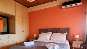 Ein Schlafzimmer mit Bett, Holzschrank und Klimaanlage.