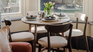 A dining area with a round table set for four, surrounded by wooden chairs.