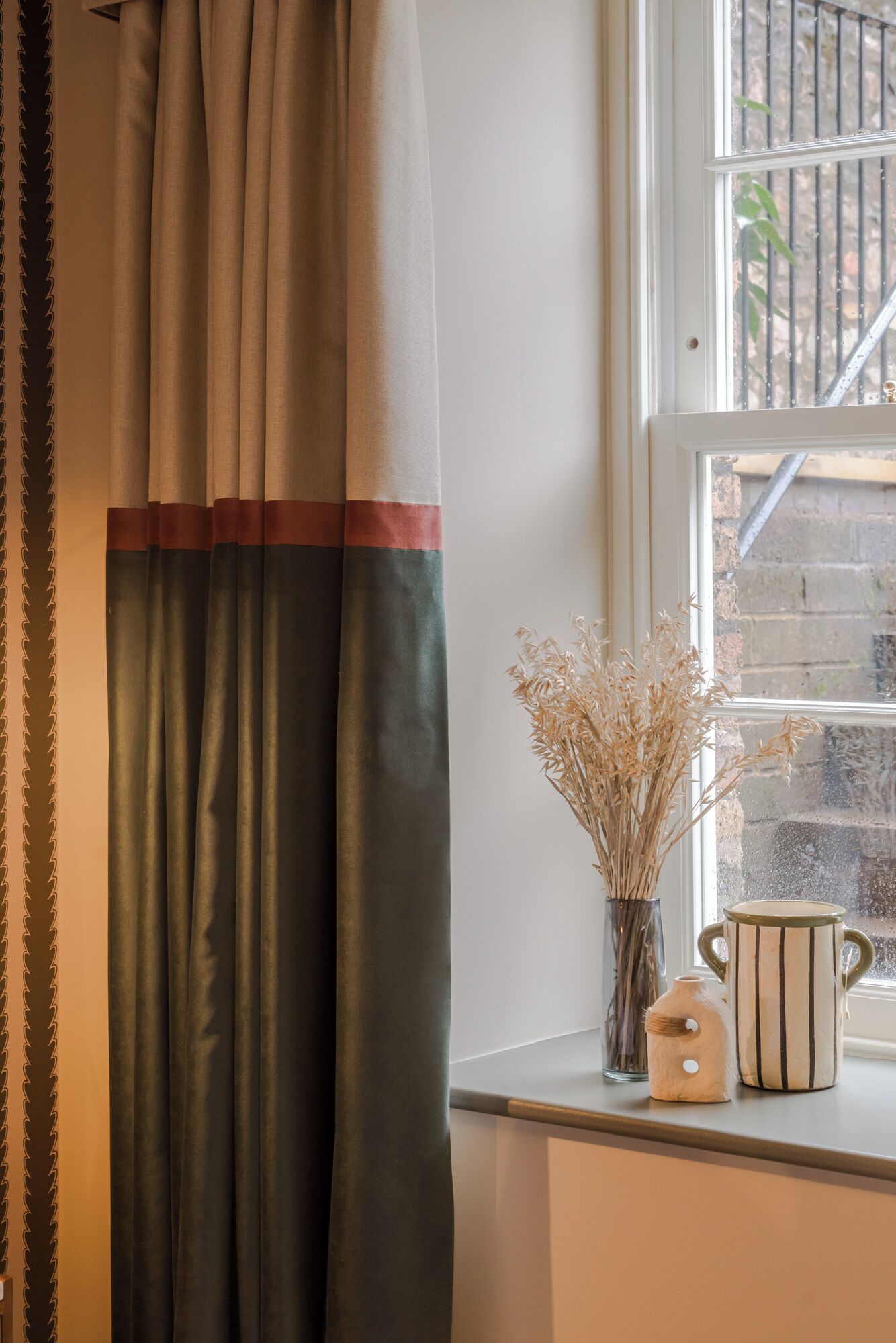 A window with a view of a brick wall and a metal railing.