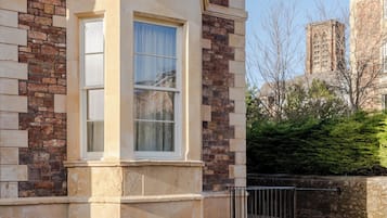 A corner building with a stone facade, two windows, and a black metal fence.