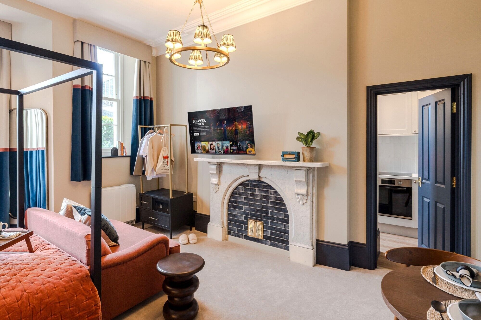 A hotel room with a bed, a sitting area, a fireplace, a TV, and a wardrobe.
