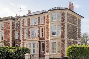 A multi-story building with a stone facade, large windows, and a corner entrance. - Your Apartment - Pembroke House (Bristol)