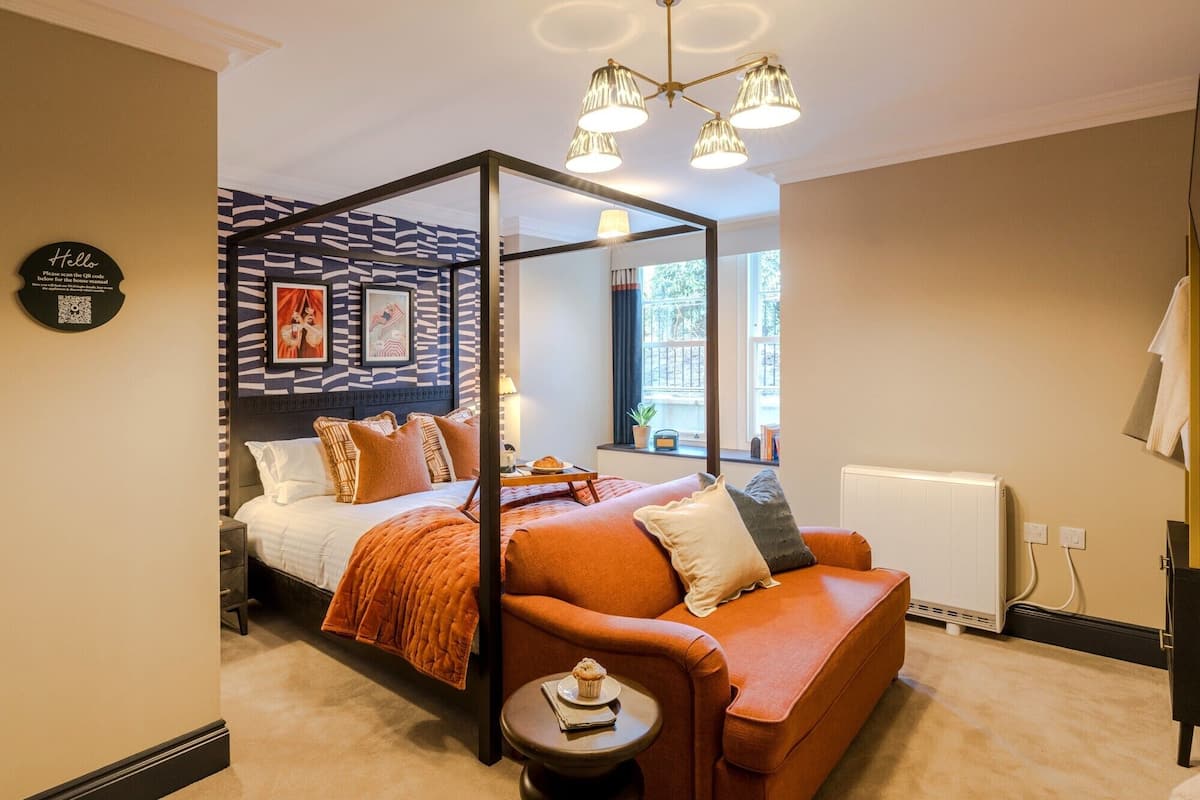 Quarto moderno com uma cama de dossel de vidro, um sofá e uma pequena mesa com um muffin.