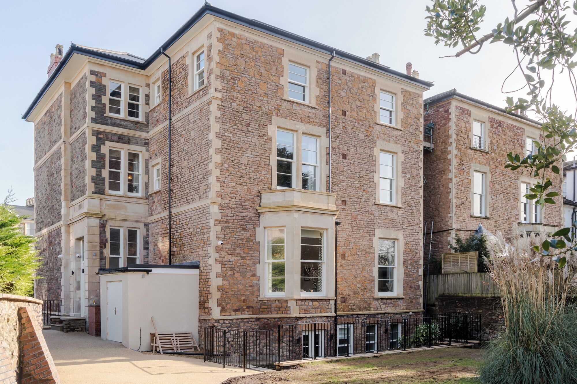 A multi-story residential building with stone facade, multiple windows, and a gated entrance.