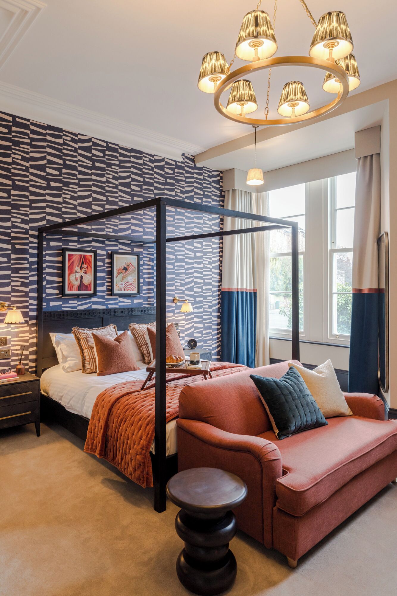 Un dormitorio con cama con dosel, sofá rojo y candelabro.