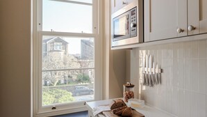 A kitchen with a large window, a microwave, and a knife rack.
