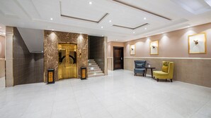 Eine geräumige Lobby mit einer Marmortreppe, einem Empfangsbereich und einer Sitzecke mit zwei Stühlen.