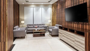 Ein modernes Wohnzimmer mit einer Sofagarnitur, einem Couchtisch und einem an einer Holzwand montierten Fernseher.