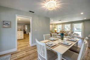 A dining area with a white table set for four, surrounded by white chairs.