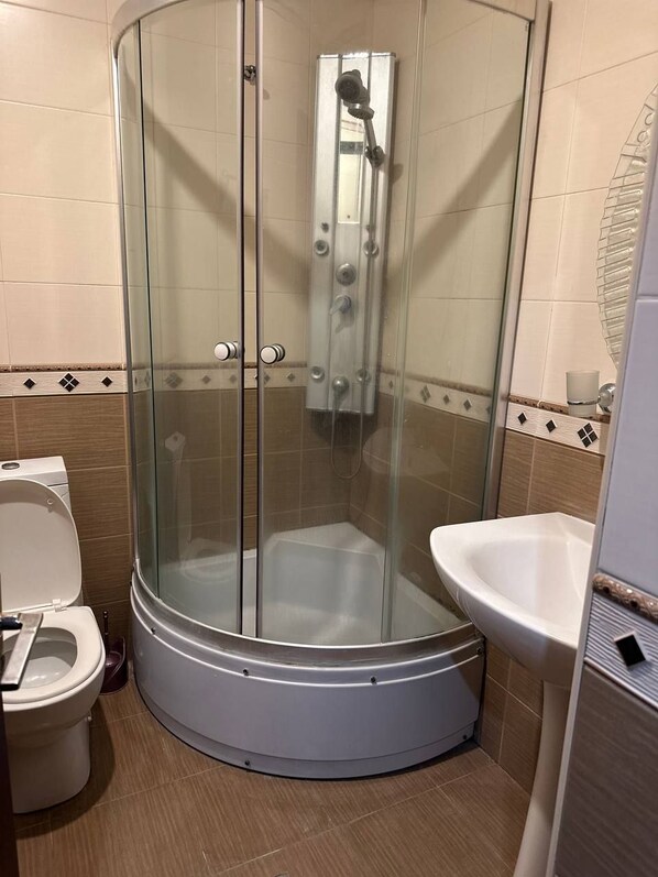 A shower enclosure with a glass door, a toilet, and a sink. - Nork Residence Hotel (Yerevan)