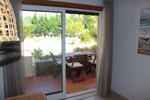 A room with a sliding glass door leading to an outdoor patio with a wooden table and chairs.
