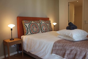 A neatly made bed with a patterned pillow, a bedside lamp, and a folded towel on the nightstand.