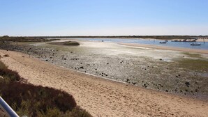 A beach with a sandy shore, a calm water body, and a small pier with boats.