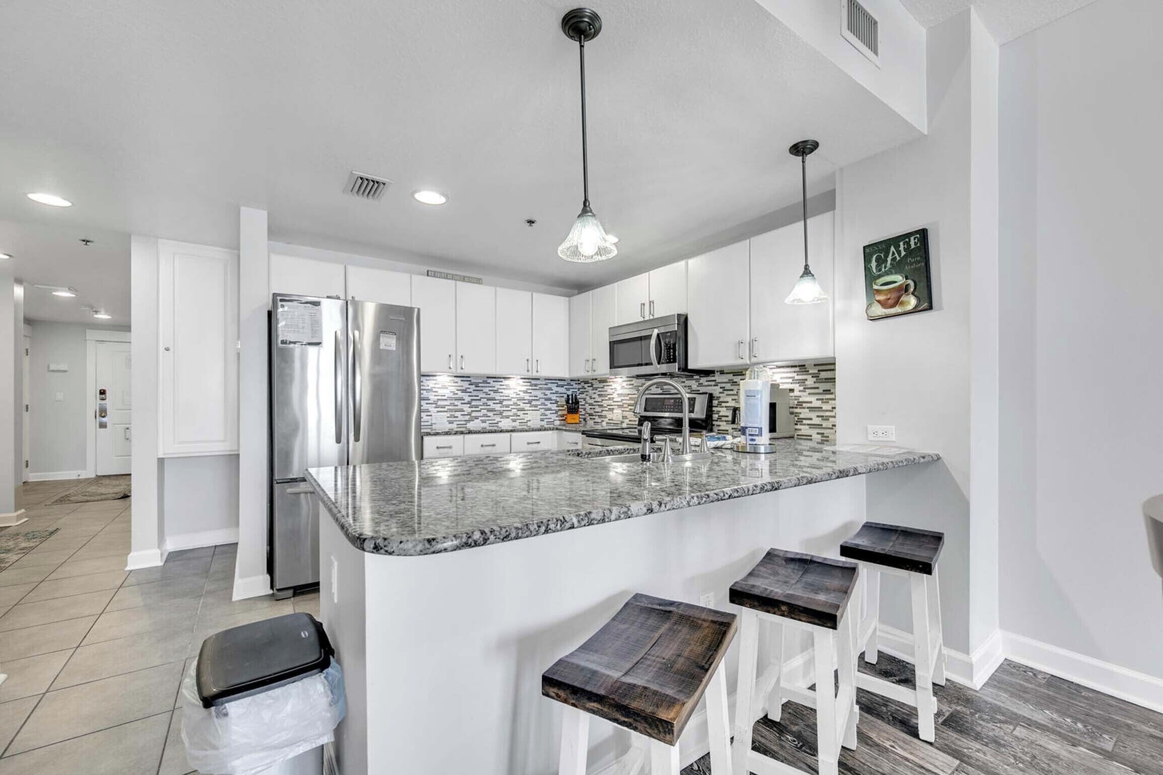 Una cocina moderna con una isla central, electrodomésticos de acero inoxidable y un salpicadero con un diseño de mosaico.