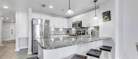 Una cocina moderna con una isla central, electrodomésticos de acero inoxidable y un salpicadero con un diseño de mosaico.