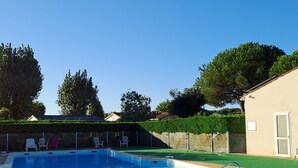 A swimming pool with a hot tub, surrounded by a fence and trees. - Mobil home 4 places terrasse couverte à 2 pas de la plage. Animaux non acceptés (Marennes-Hiers-Brouage)