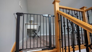 A wooden staircase with black metal railings and a black safety gate at the top.