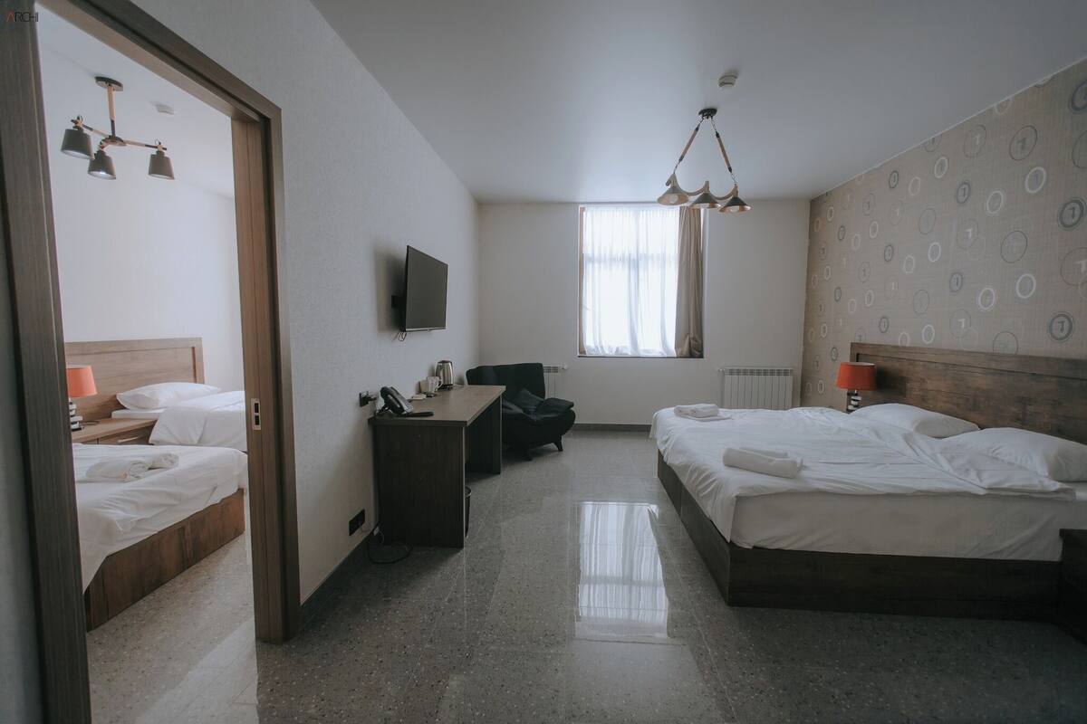 A hotel room with a bed, a desk, a chair, a television, and a window with curtains.