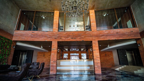 Eine geräumige Lobby mit Marmorboden, einem prunkvollen Kronleuchter und einer Treppe zu einer oberen Ebene.
