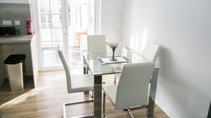Una cucina moderna con mobili bianchi, un tavolo da pranzo in vetro e quattro sedie bianche.