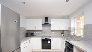 Una cucina moderna con mobili bianchi, forno integrato, microonde ed elettrodomestici.