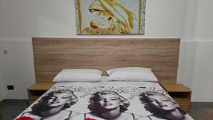 A bed with a patterned bedspread, a wooden headboard, and two bedside tables. - B&B Sant'Antonio (Gallipoli)