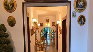 A hallway with a decorative archway, framed artwork, and a potted plant. - B&B Sant'Antonio (Gallipoli)