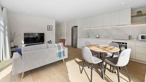 A modern living room with a sofa, TV, and dining area with chairs and a table. - Close to the remarkable ski field, modern and warm. (Queenstown)