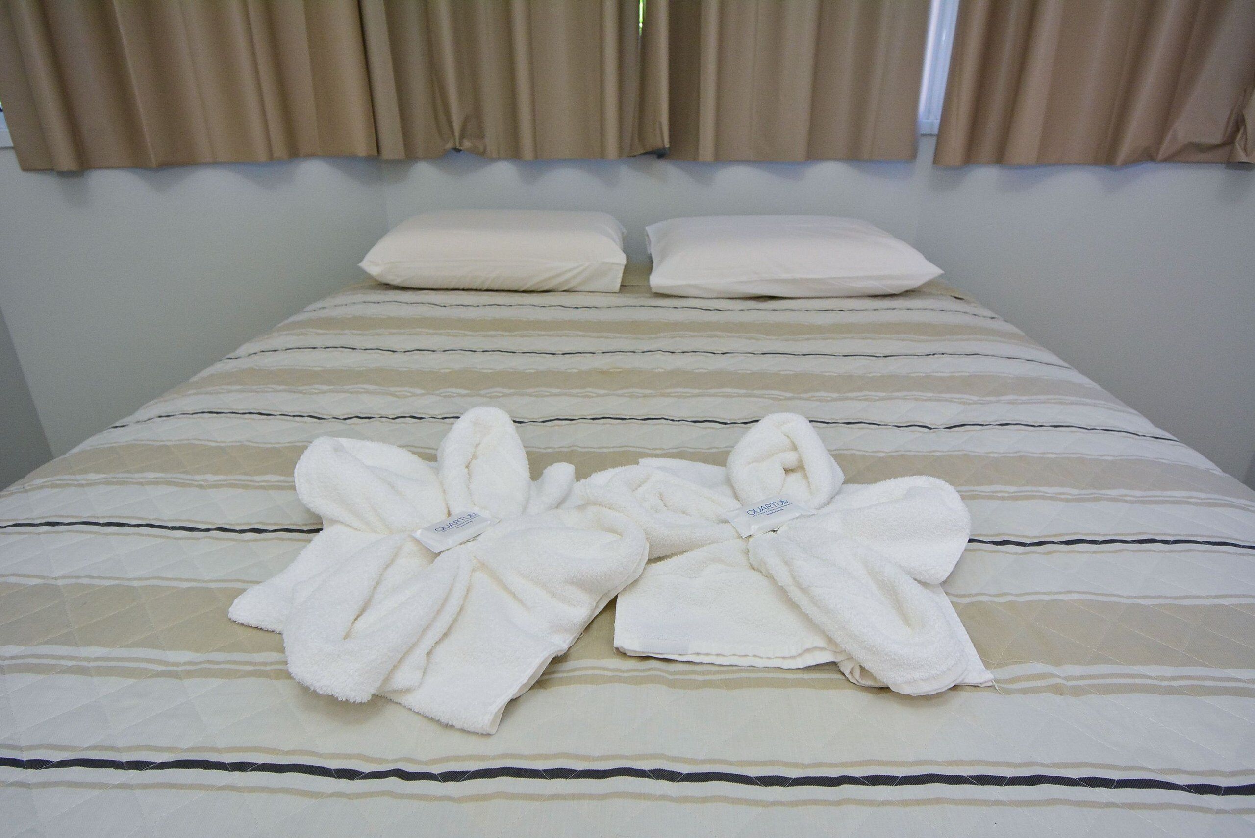 Una cama bien hecha con ropa de cama a rayas y dos almohadas.