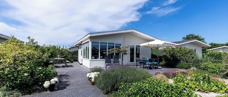 Enjoy a peaceful retreat with a patio area, table, and chairs, surrounded by well-maintained gardens and large windows.