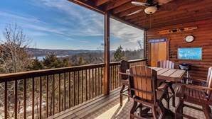 A wooden deck with a table and chairs, a clock, and a sign reading "On Lake Time". - 2BR Village At Indian Point 1306 near SDC - Free Tickets Daily up to $500 (Branson)