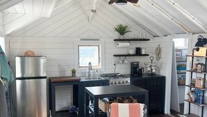 A compact kitchen with a central island, a built-in stove, and a refrigerator. - Lovely studio steps to the beach in Dennis port (Dennis)